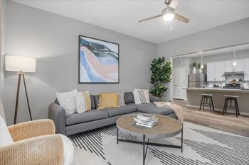 A living room with a grey couch, a round coffee table, and a painting on the wall.